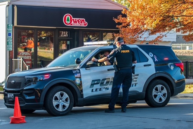 Police officer speaking to another police officer in their vehicle.